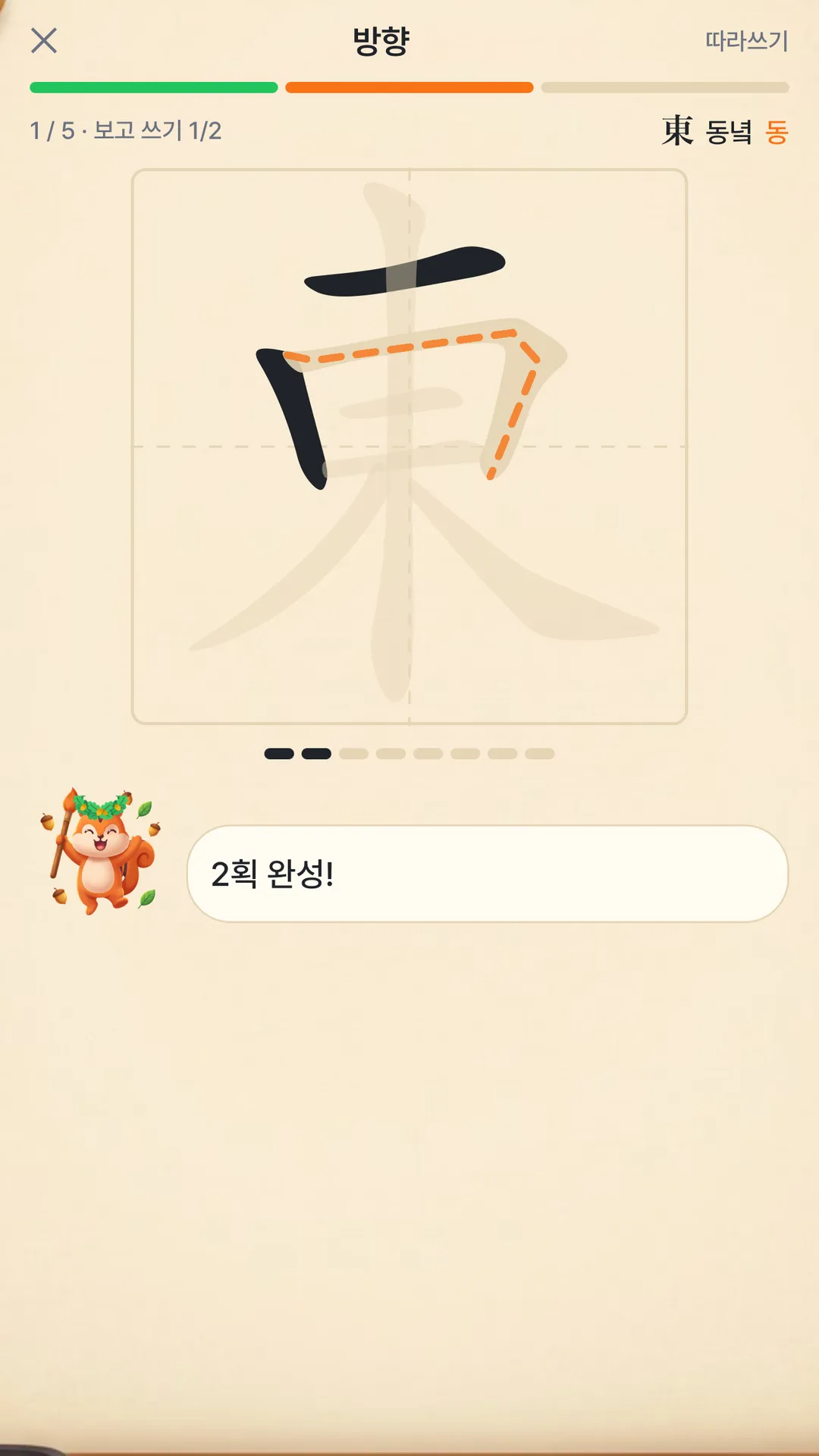 한자 급수왕 따라쓰기 화면: 東(동녘 동)을 획순대로 따라 쓰는 모눈 칸과 다음 획을 알려 주는 주황 점선, 붓돌이의 '2획 완성!' 말풍선